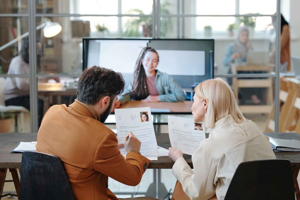 Engineering leaders reviewing candidate resumes during remote video interview with nearshore candidate, evaluating cultural fit and collaboration potential for team integration.