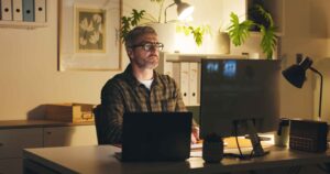 Software engineer focused on development work at home office setup, representing remote productivity and concentrated problem-solving in software delivery