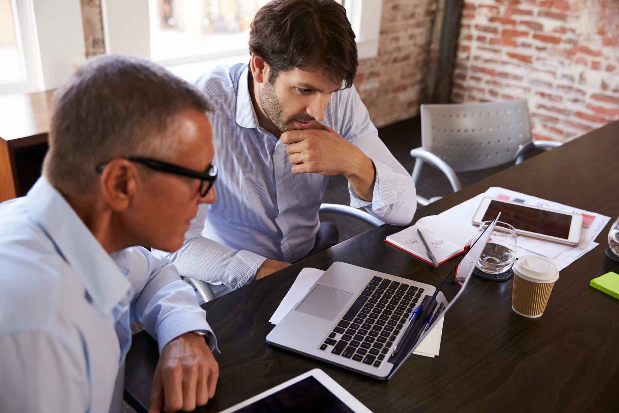 Two engineering professionals discussing and evaluating technical issues, demonstrating problem assessment and decision-making in software project management.